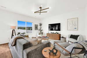 Bright living area featuring wood-finish flooring, a contemporary ceiling light fixture, and a large window