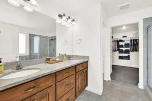 Double vanity with undermount sinks, speckled stone countertops, and wood-finish cabinetry