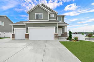 Contemporary two-story residence featuring a two-car garage, prominent front landscaping, a concrete driveway, and a welcoming entryway