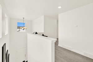 Bright hallway with recessed lighting and neutral-toned carpeting