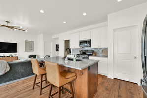 Kitchen island with granite countertop and integrated sink, featuring wood-finish flooring