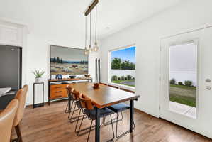 Open-concept dining area featuring wood-finish flooring, a large window, and a glass-paneled exterior door