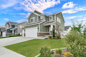 Two-story residence featuring sage green siding, white trim, and a brick accent foundation