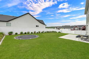 Expansive backyard featuring a manicured lawn, a large concrete patio, and a privacy fence