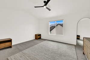 Spacious room featuring neutral carpet flooring, a modern black ceiling fan, and a window with mountain scenery