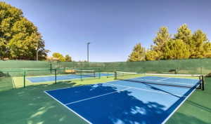 Multiple outdoor courts featuring blue and green surfacing, perimeter fencing, and built-in lighting