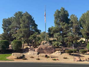 Stone Cliff entrance featuring boulder signage, layered stone landscaping, mature pine trees, and established palm trees