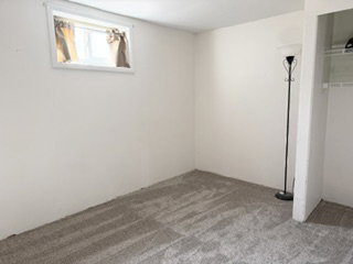 Carpeted room featuring a window with white trim, a built-in closet with shelving, and light-colored walls