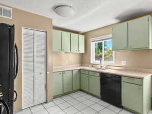 Kitchen featuring a double basin stainless steel sink, black dishwasher, and white tiled flooring