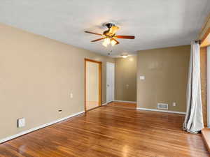 Spacious room featuring wood-finish flooring, light tan walls, and white trim
