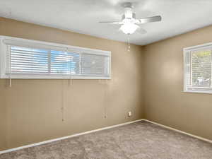 Room featuring neutral-toned walls, carpeted flooring, and a ceiling fan with integrated lighting