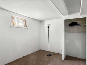 Windowed room featuring white walls and textured carpet flooring