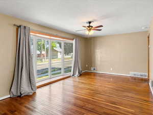 Hardwood flooring throughout featuring a multi-pane bay window