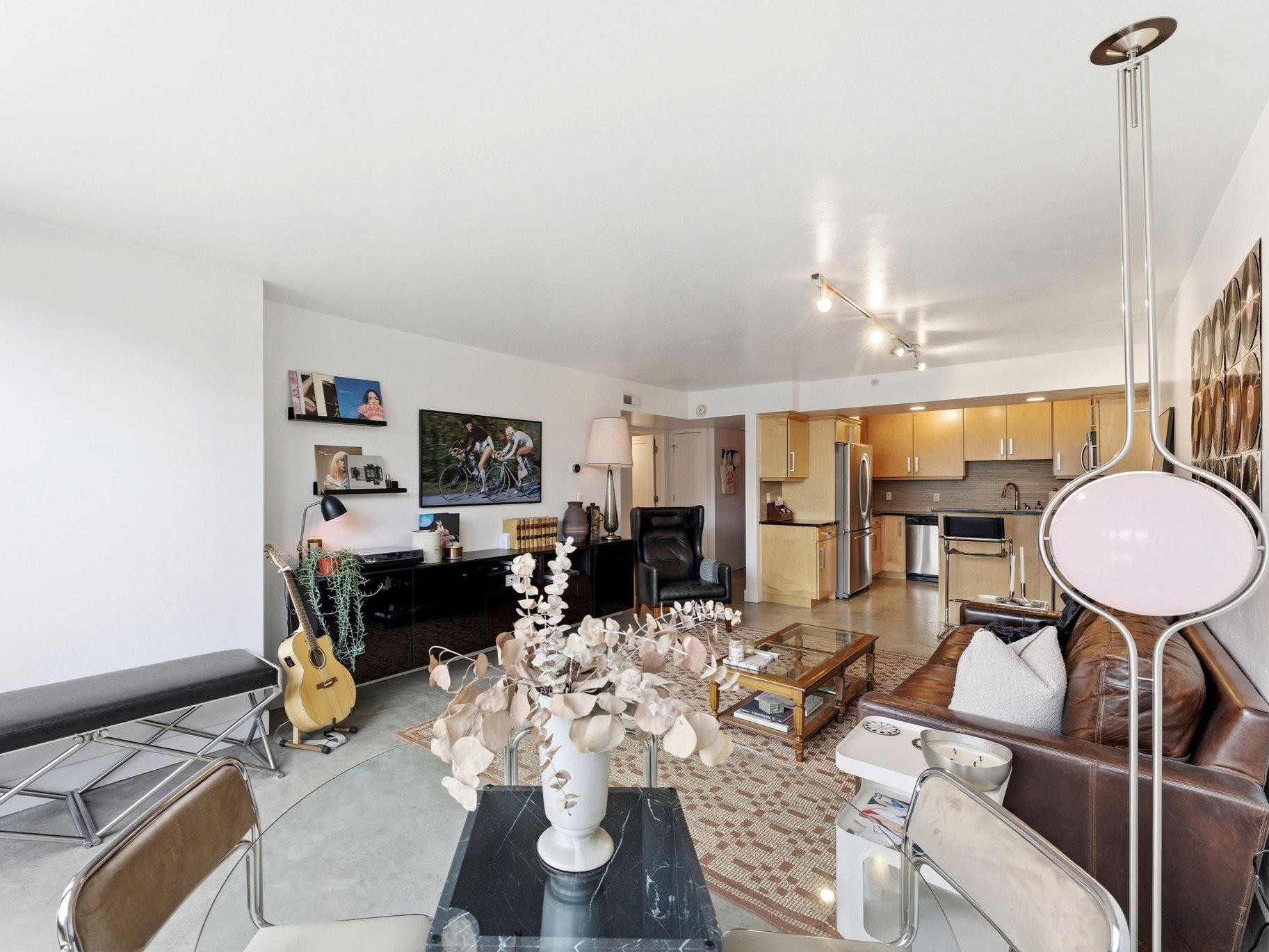 Open-concept living space featuring a full kitchen, track lighting, and hard-surface flooring