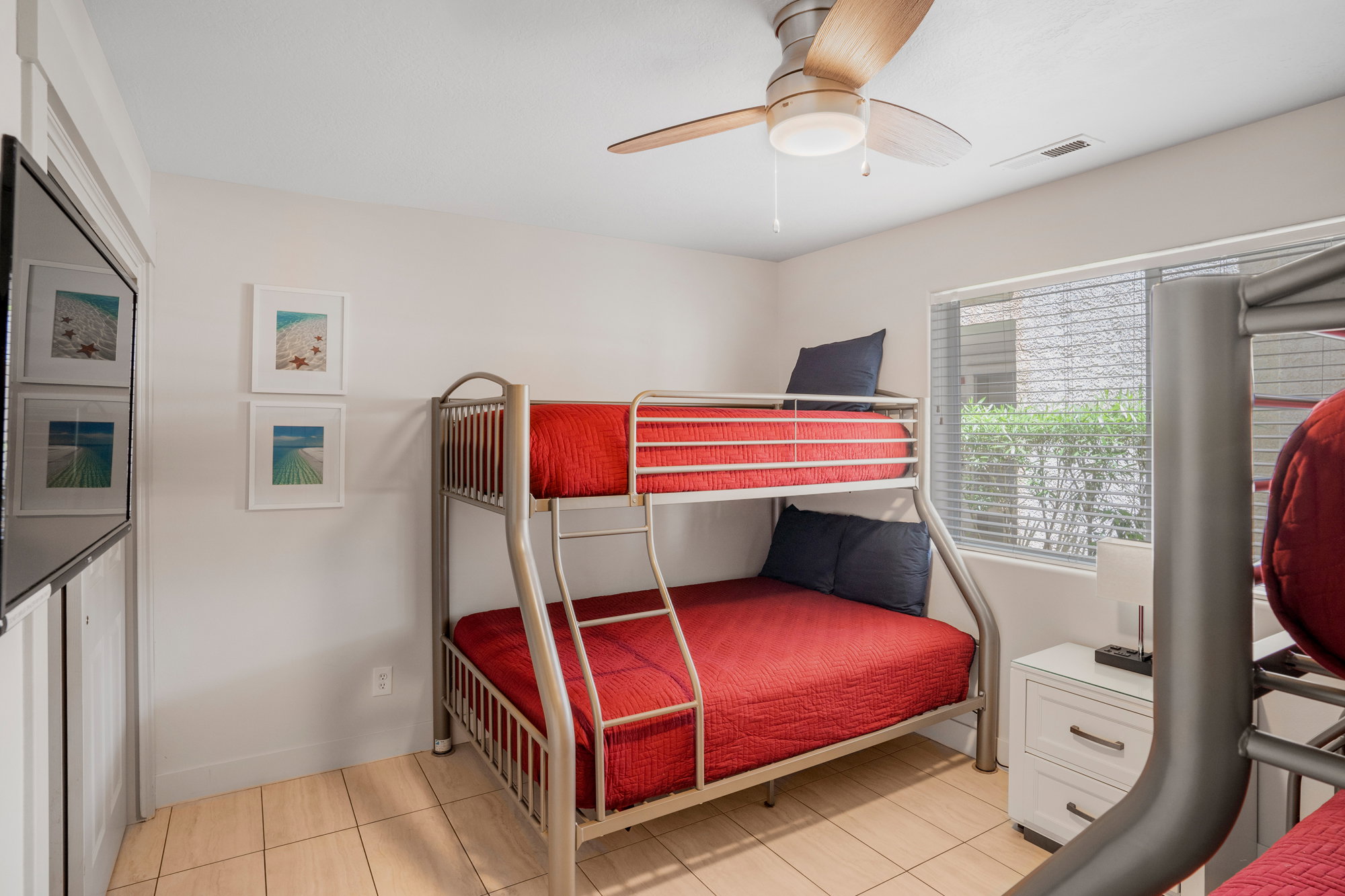 Room featuring metal bunk beds, tile flooring, and a ceiling fan with light fixture