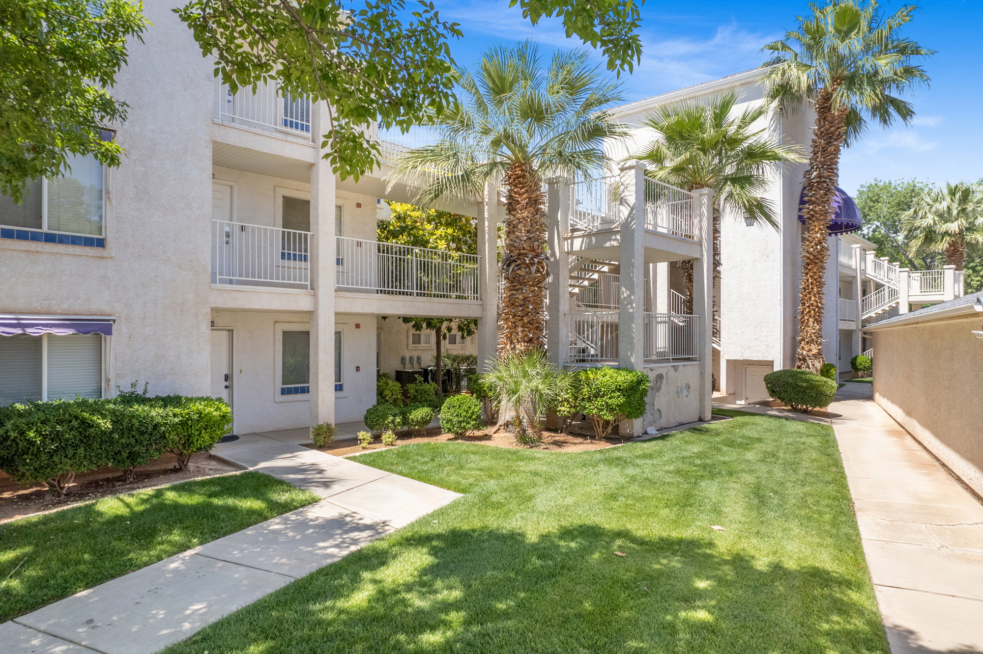 White stucco multi-story building featuring multiple balconies with white railings