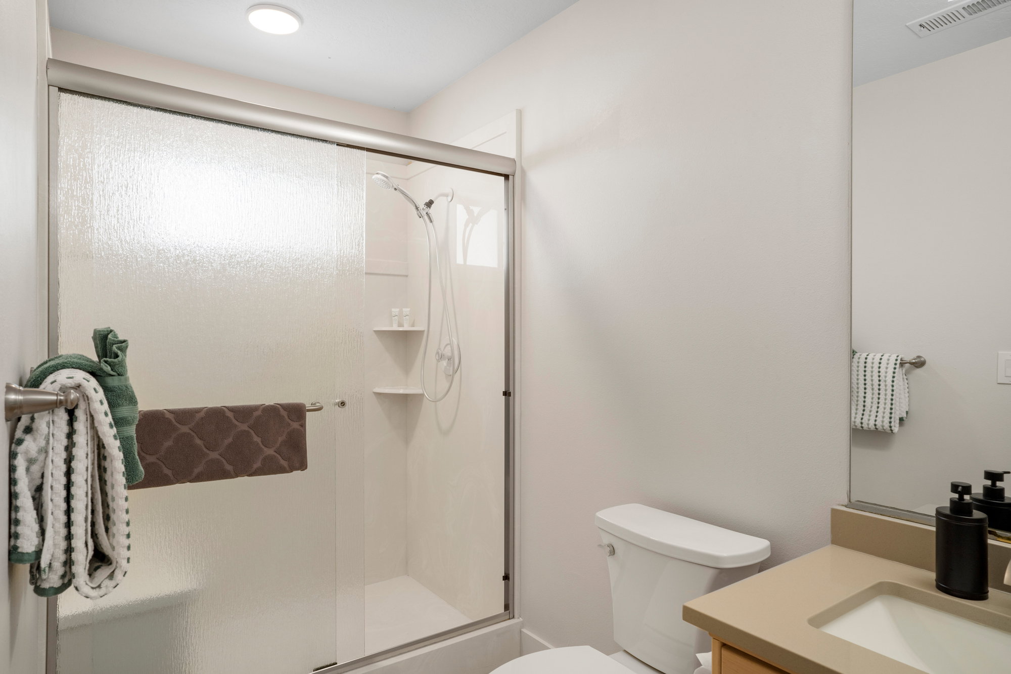 Bathroom featuring a glass-enclosed shower with integrated shelving, a built-in shower bench, and a mounted showerhead