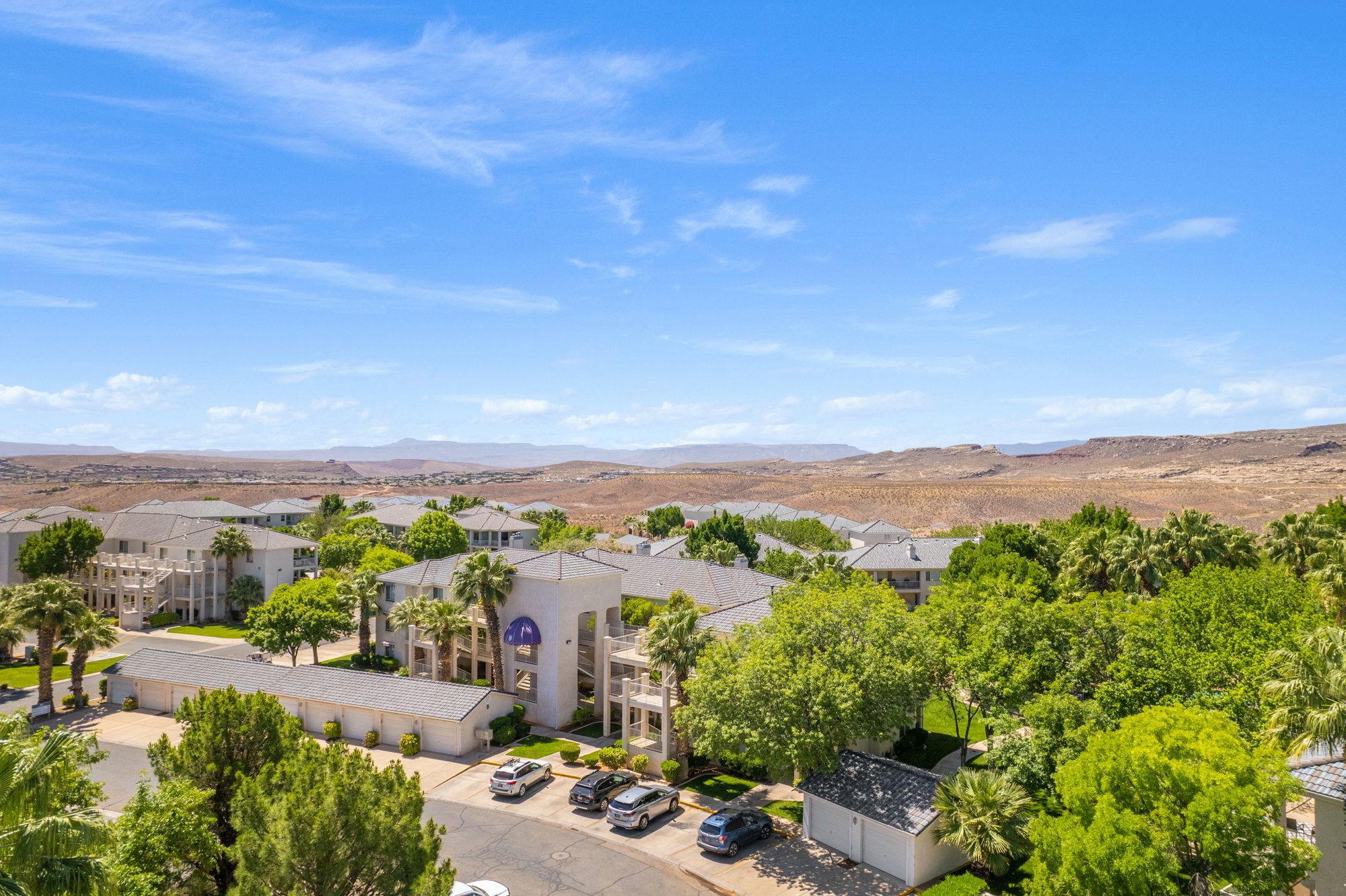 Lush green landscaping surrounding multi-story residential buildings with a desert mountain backdrop