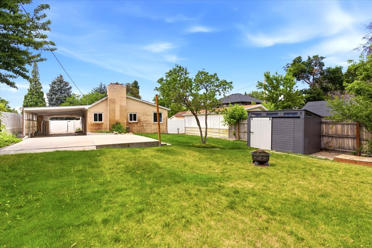 Expansive backyard featuring a green lawn, a contemporary storage shed, and a concrete patio