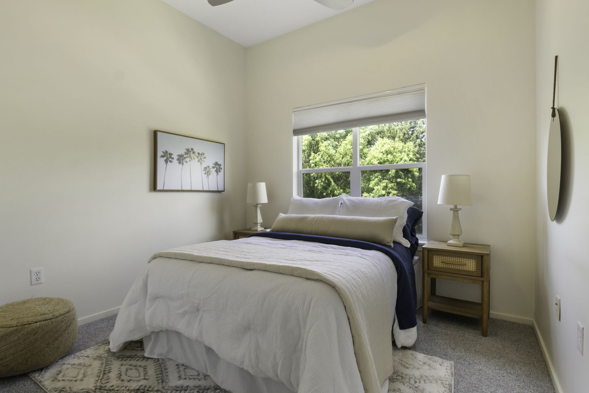 Carpeted bedroom featuring a large window, light-toned walls, and a ceiling fan