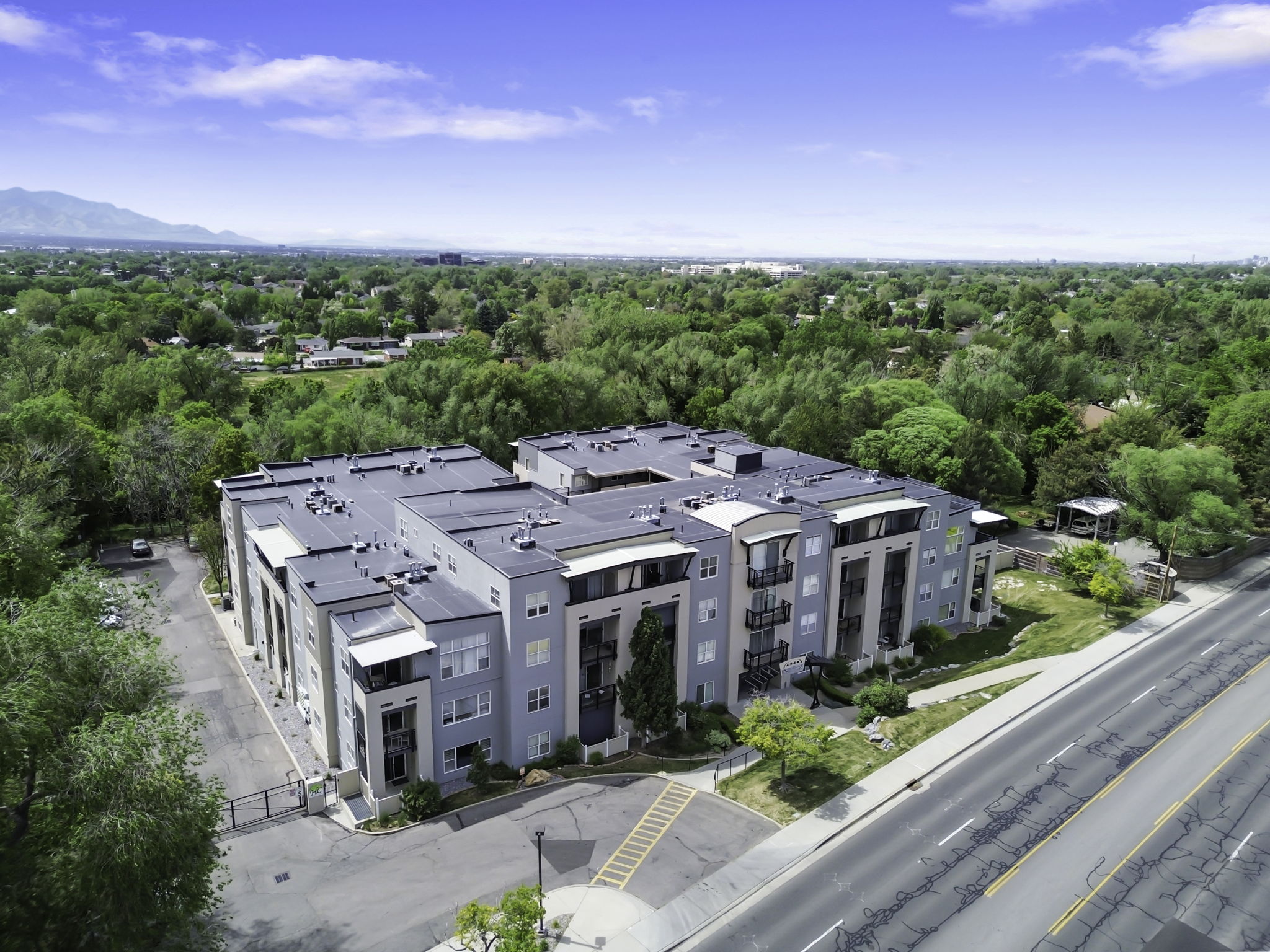Contemporary apartment complex featuring multi-story construction, private balconies, and a paved parking area
