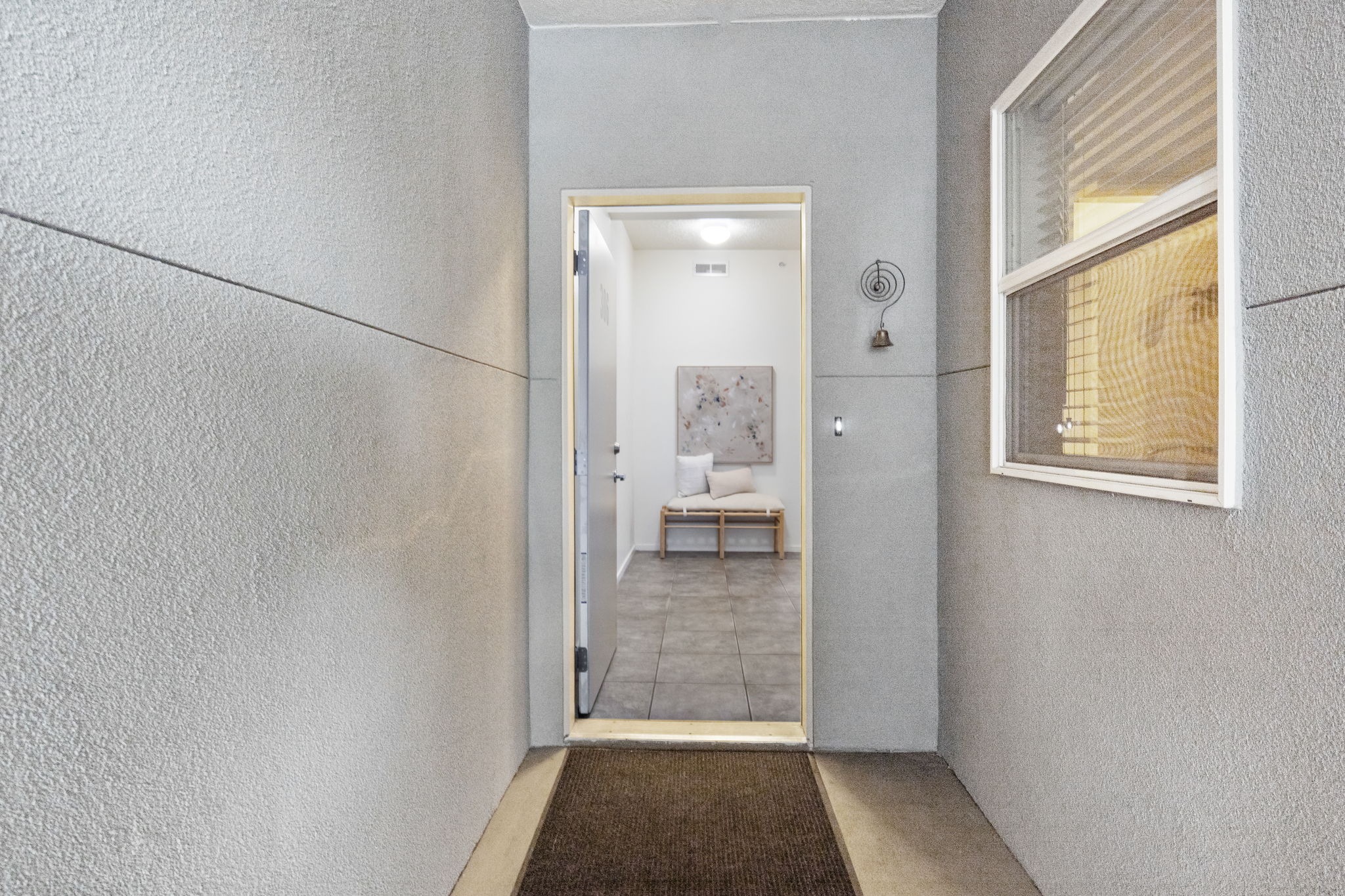 Entryway featuring textured exterior walls with a horizontal accent line, an overhead transom window, and a recessed entrance