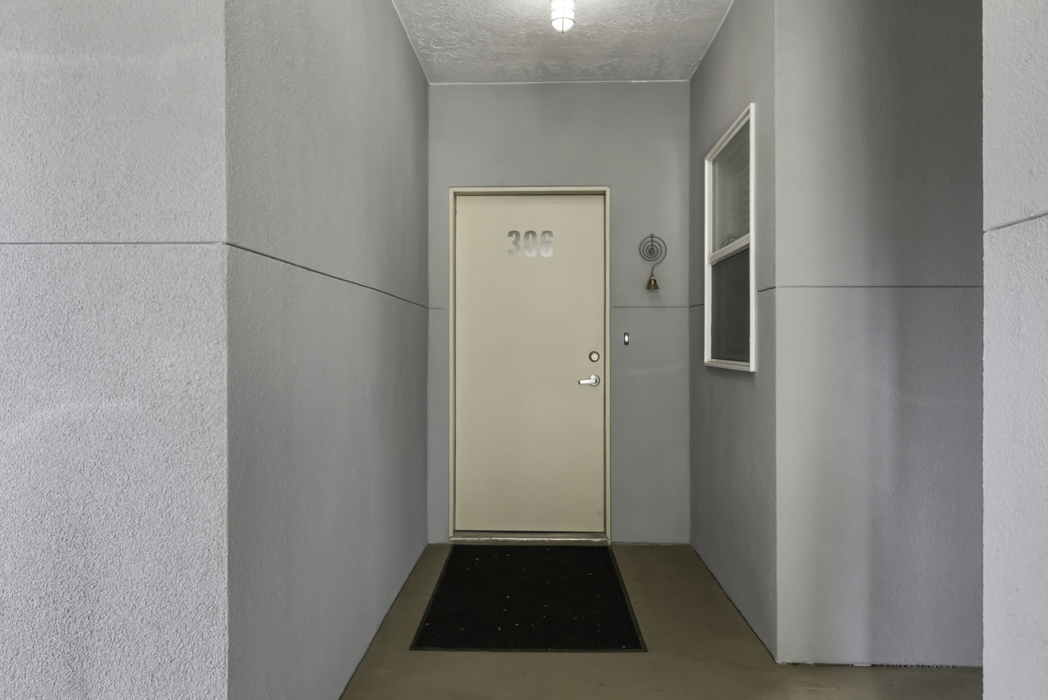 Entryway featuring a solid core door with visible numbering, a small frosted glass window, and concrete flooring