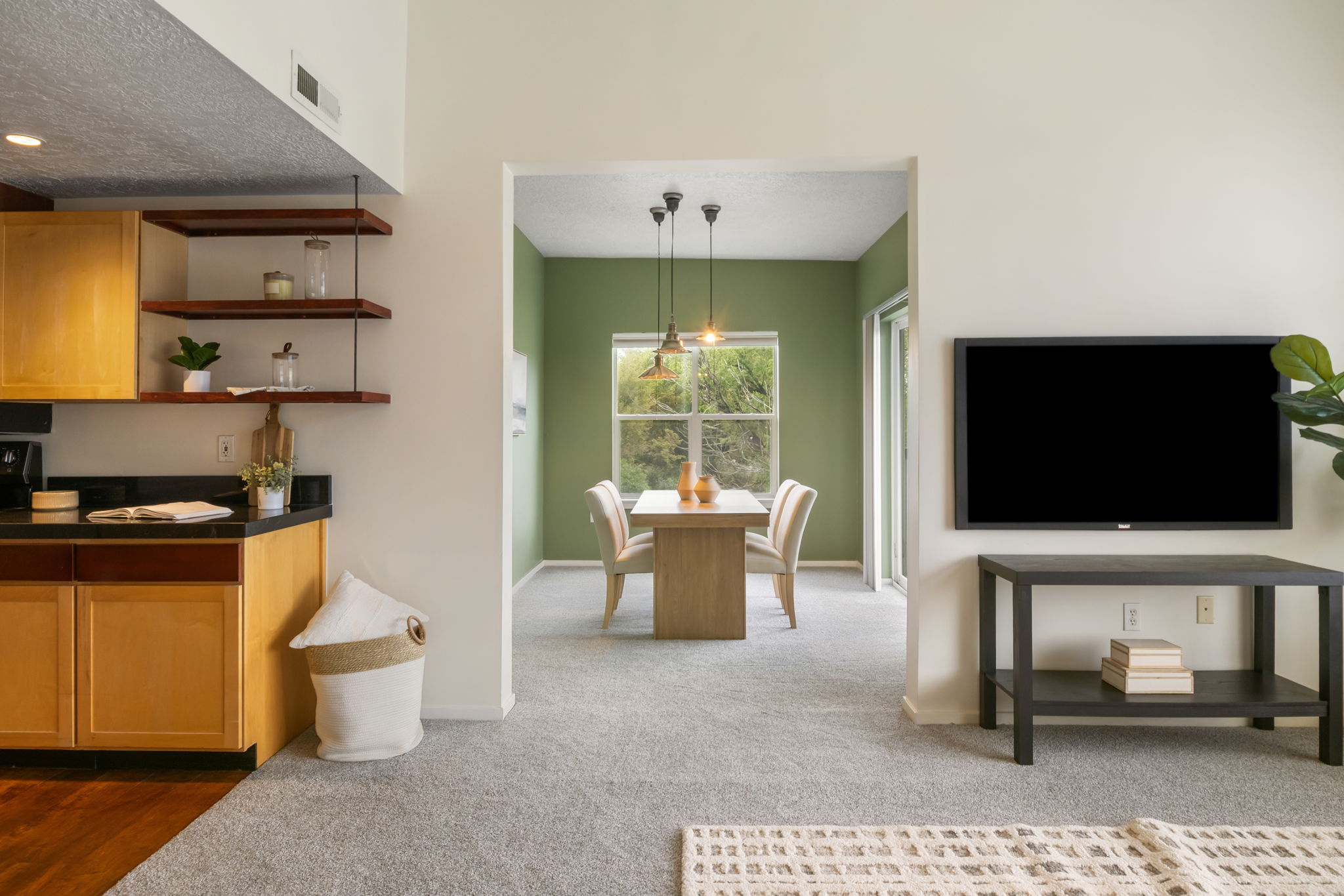 Dining area with green accent wall and pendant lighting