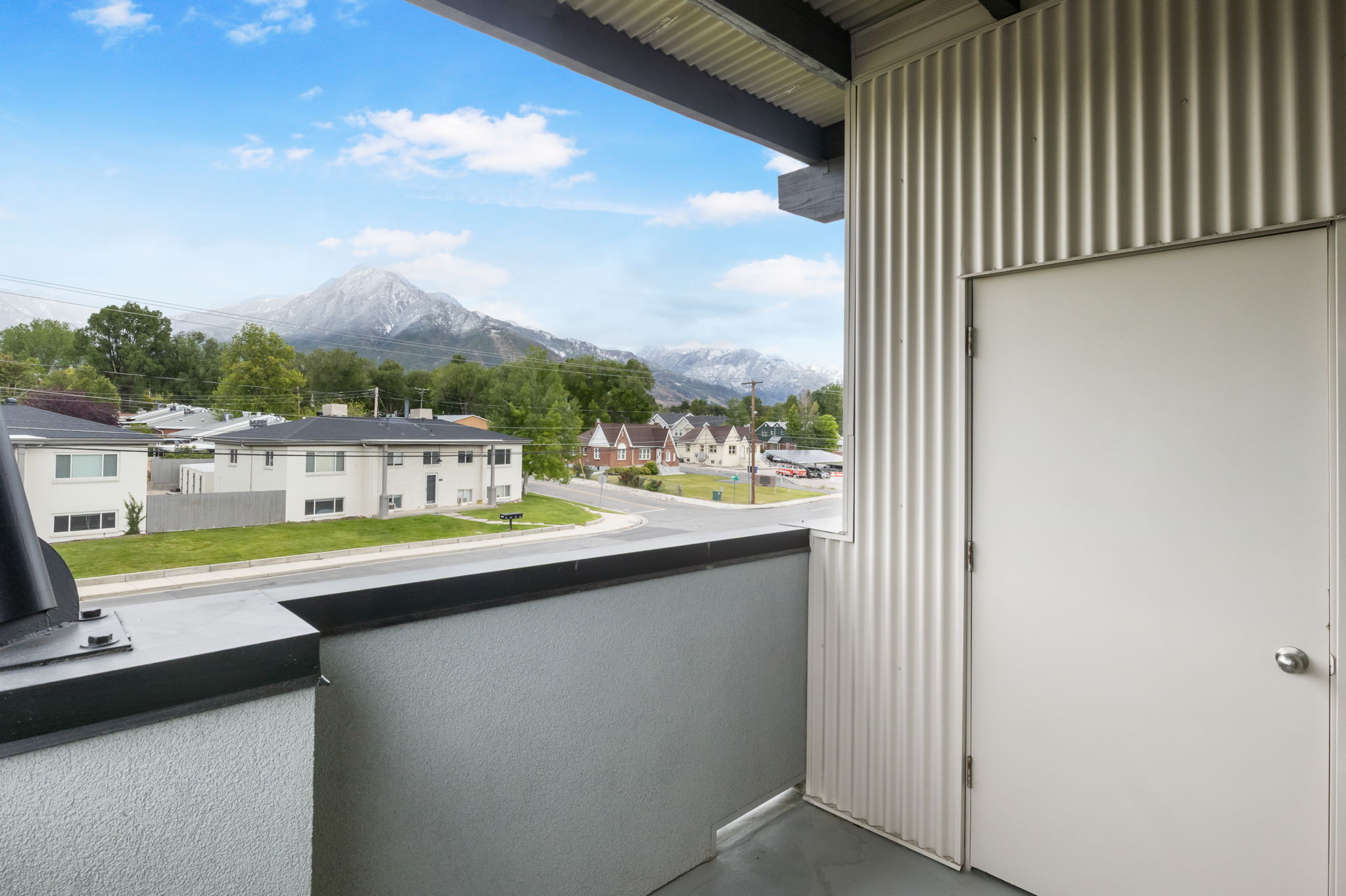 Balcony featuring a corrugated metal wall and a solid white door