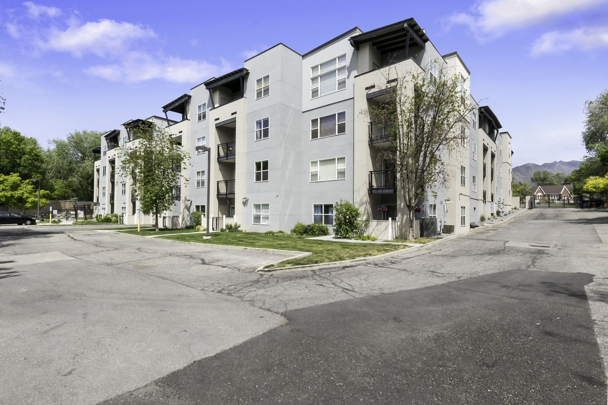 Multi-story building featuring light-colored stucco exterior, dark balcony railings, recessed balconies, and top-floor covered patios