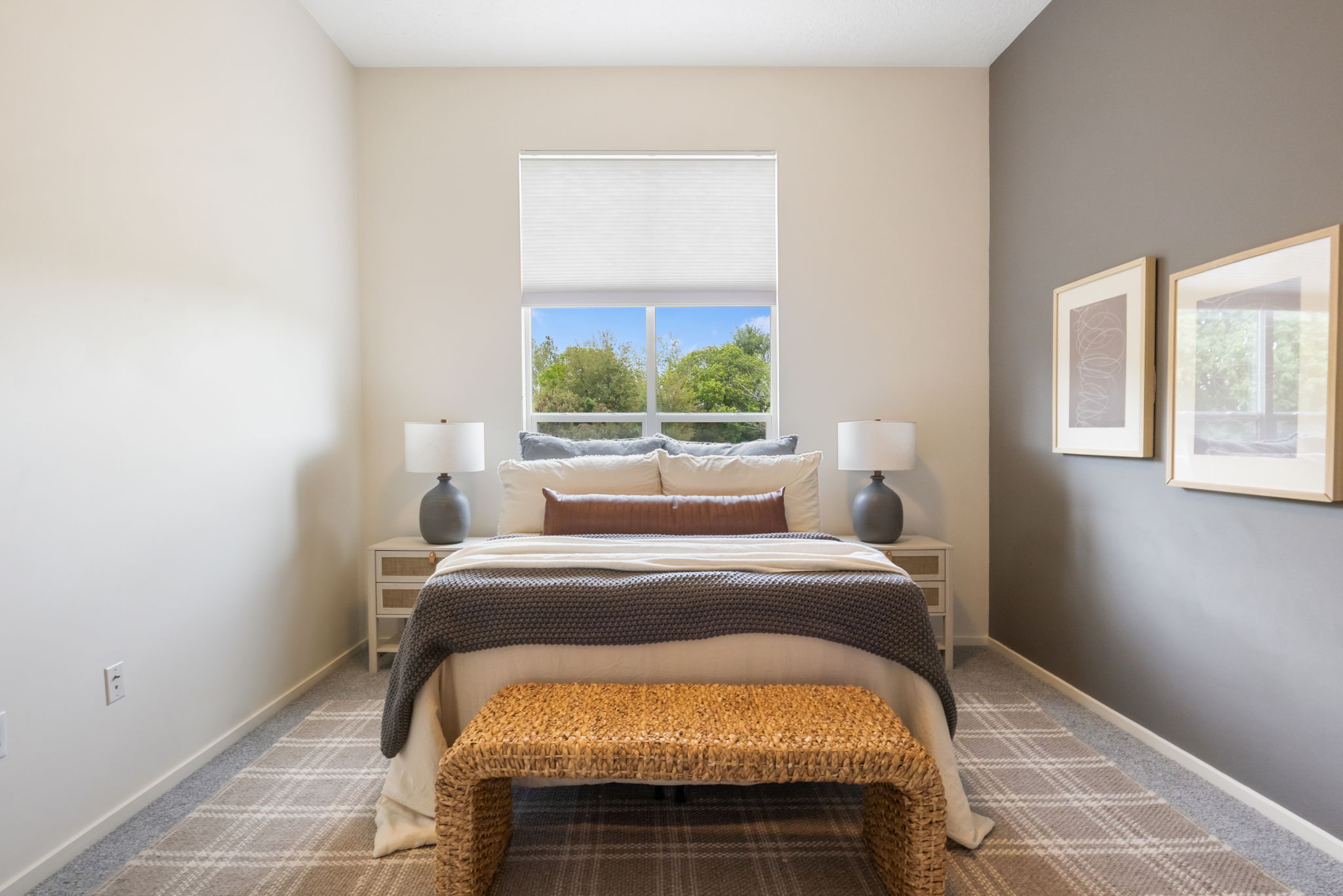 Bedroom featuring a large window, neutral walls, a contrasting accent wall, and patterned carpet flooring