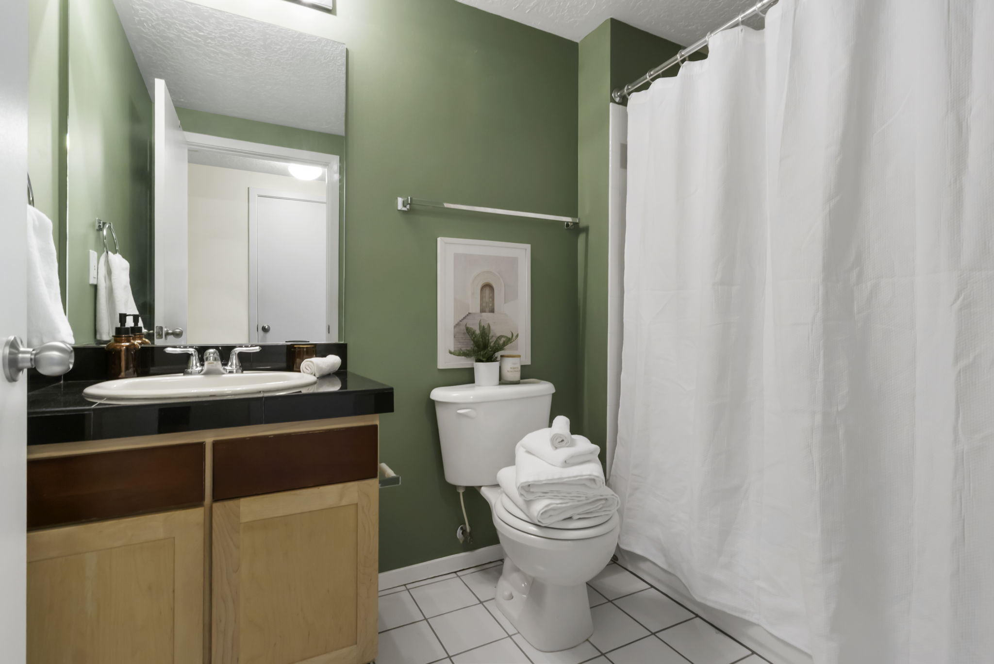 Bathroom featuring a single vanity with a black countertop, integrated sink, and chrome-finish faucet