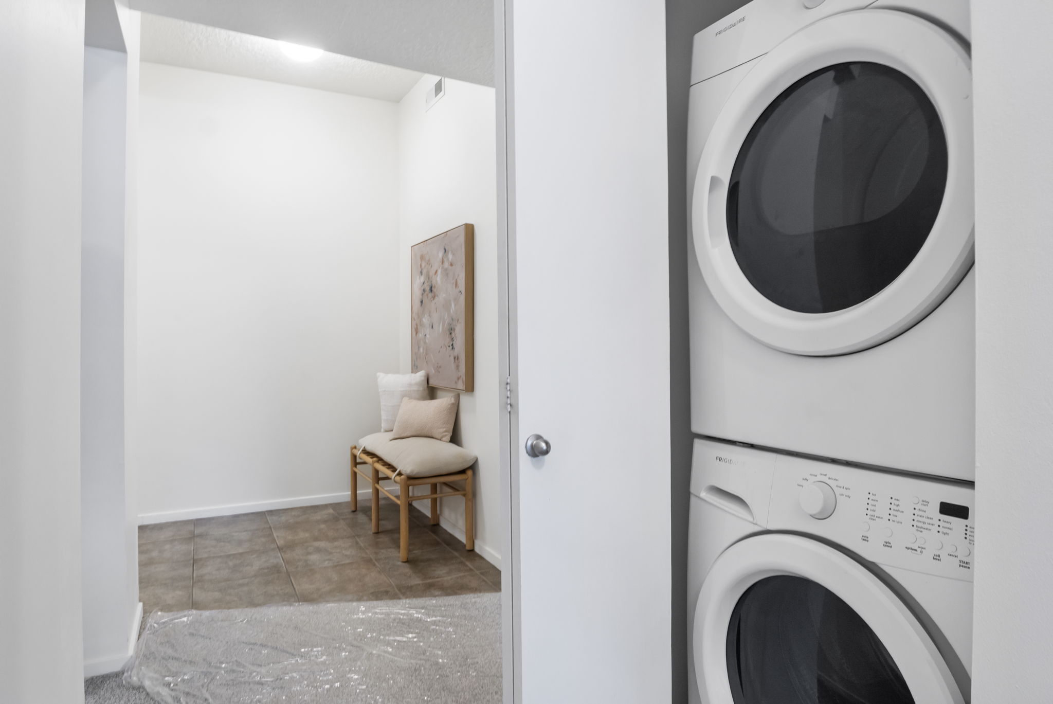 Integrated laundry closet with stacked washer and dryer, featuring a white door and chrome knob
