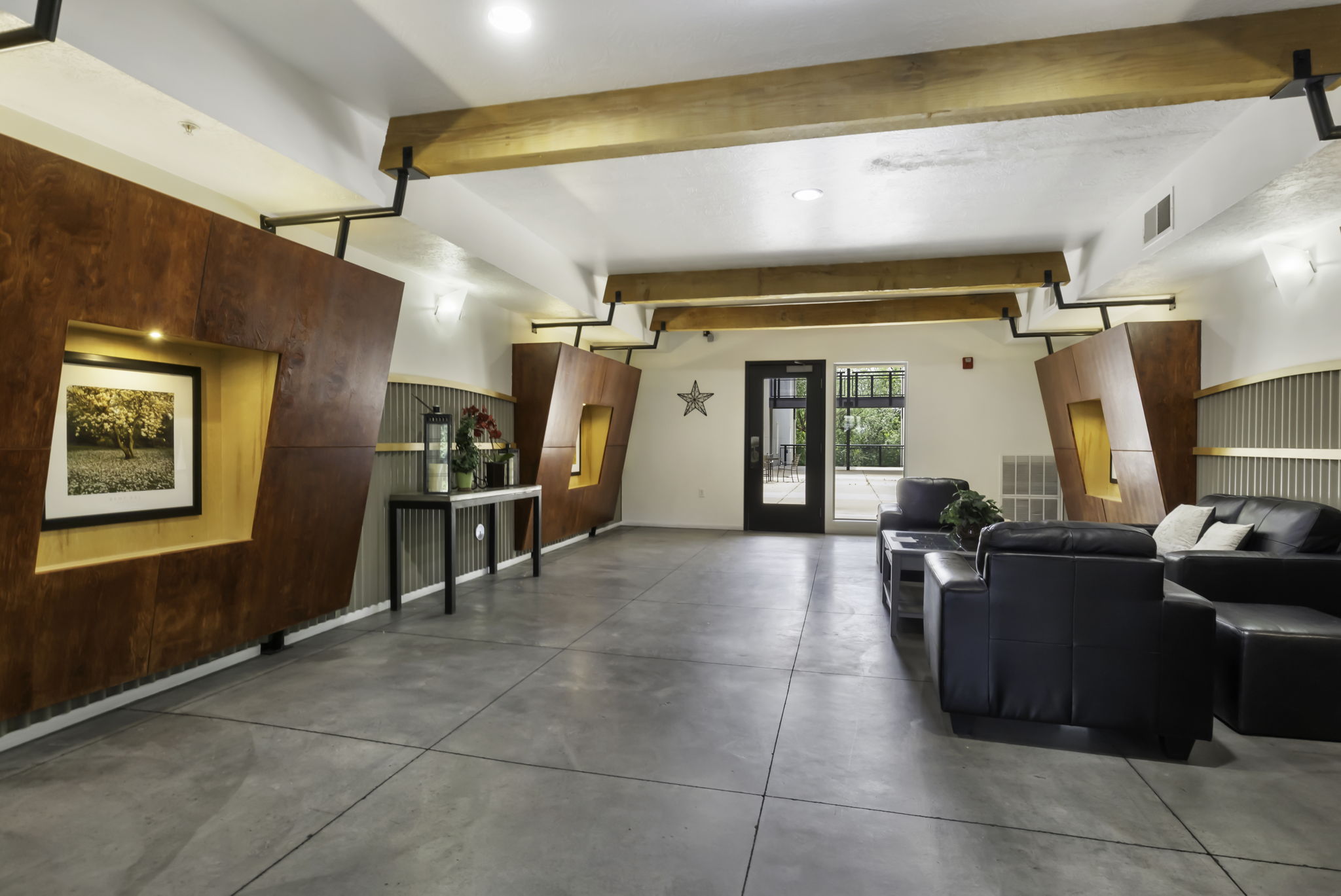 Spacious common area featuring polished concrete flooring, exposed wood beams, and accent walls with recessed lighting