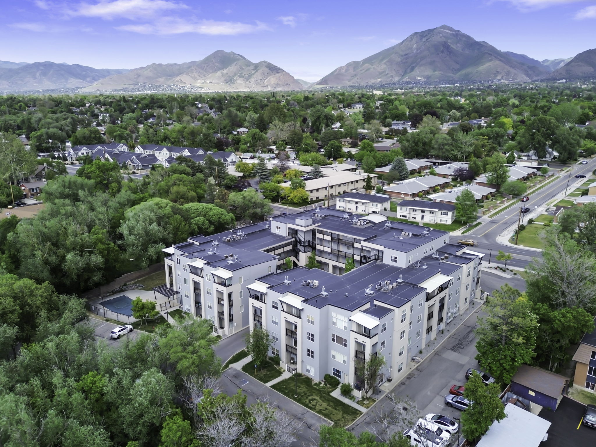 Modern multi-story residential complex featuring a dark roofline, light-toned exterior siding, and multiple balconies