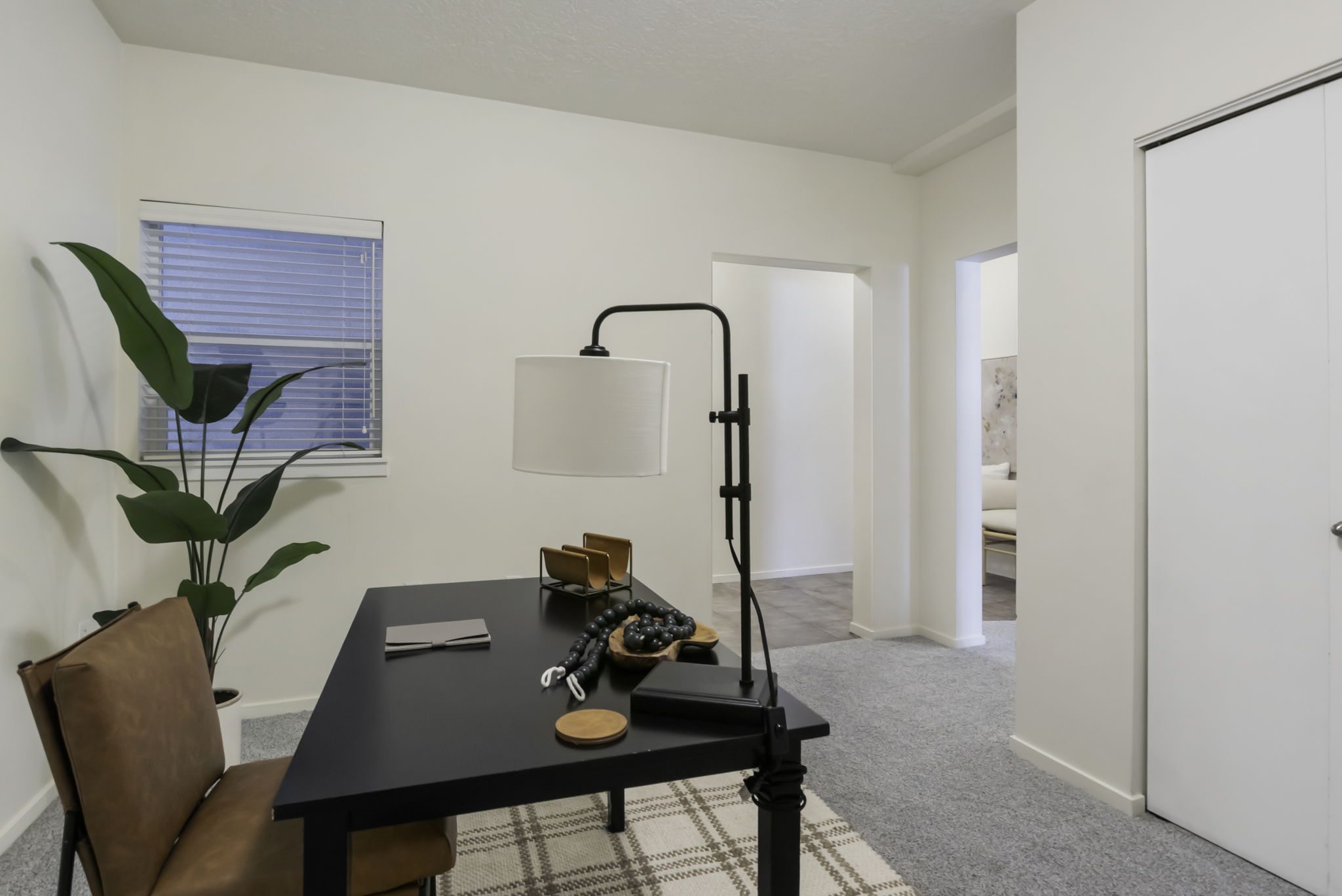 Bright interior space featuring a window with horizontal blinds, light gray carpeting, and white walls