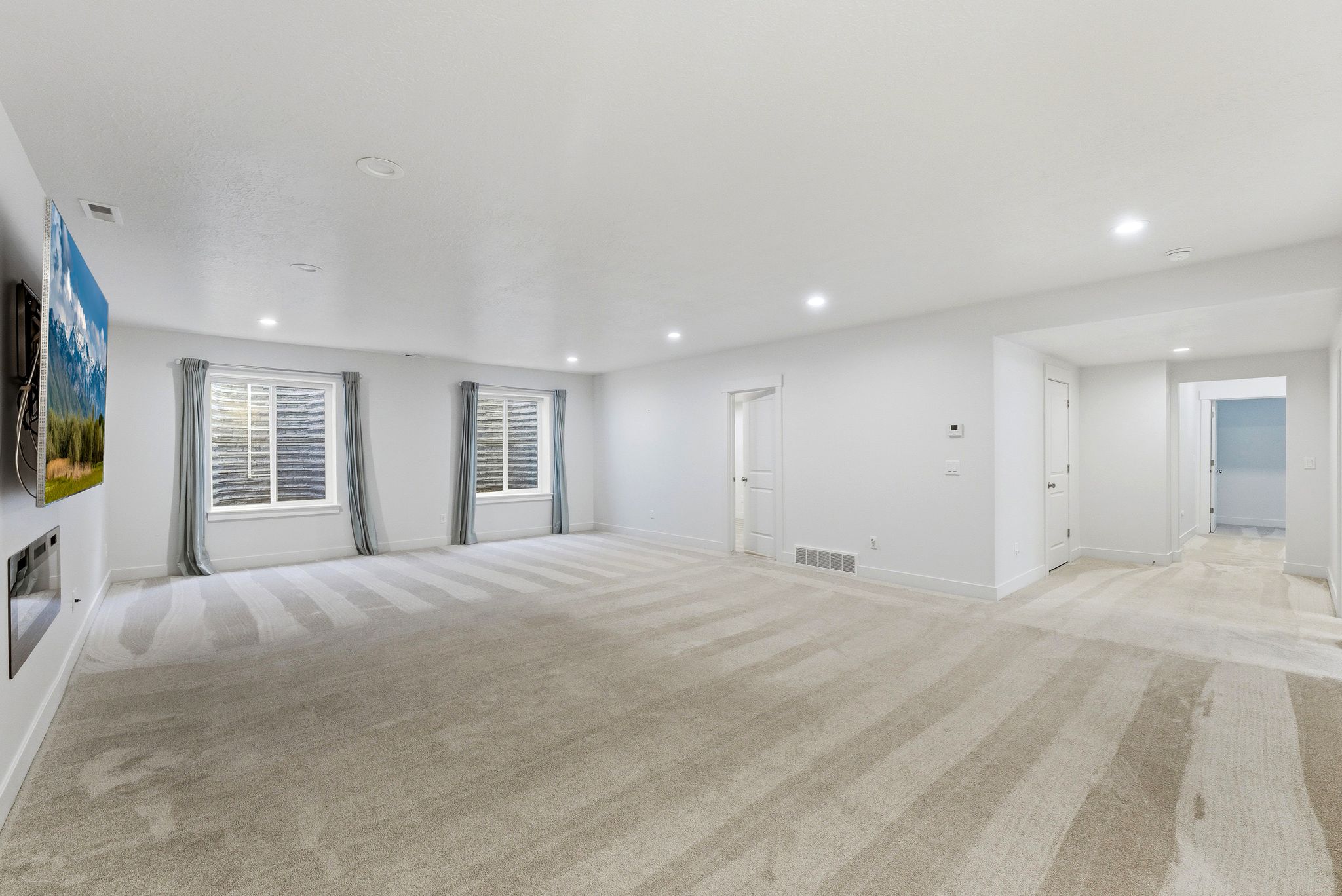 Spacious room featuring light-colored carpeting, recessed lighting, and white walls