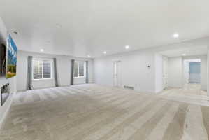 Spacious room featuring light-colored carpeting, recessed lighting, and white walls