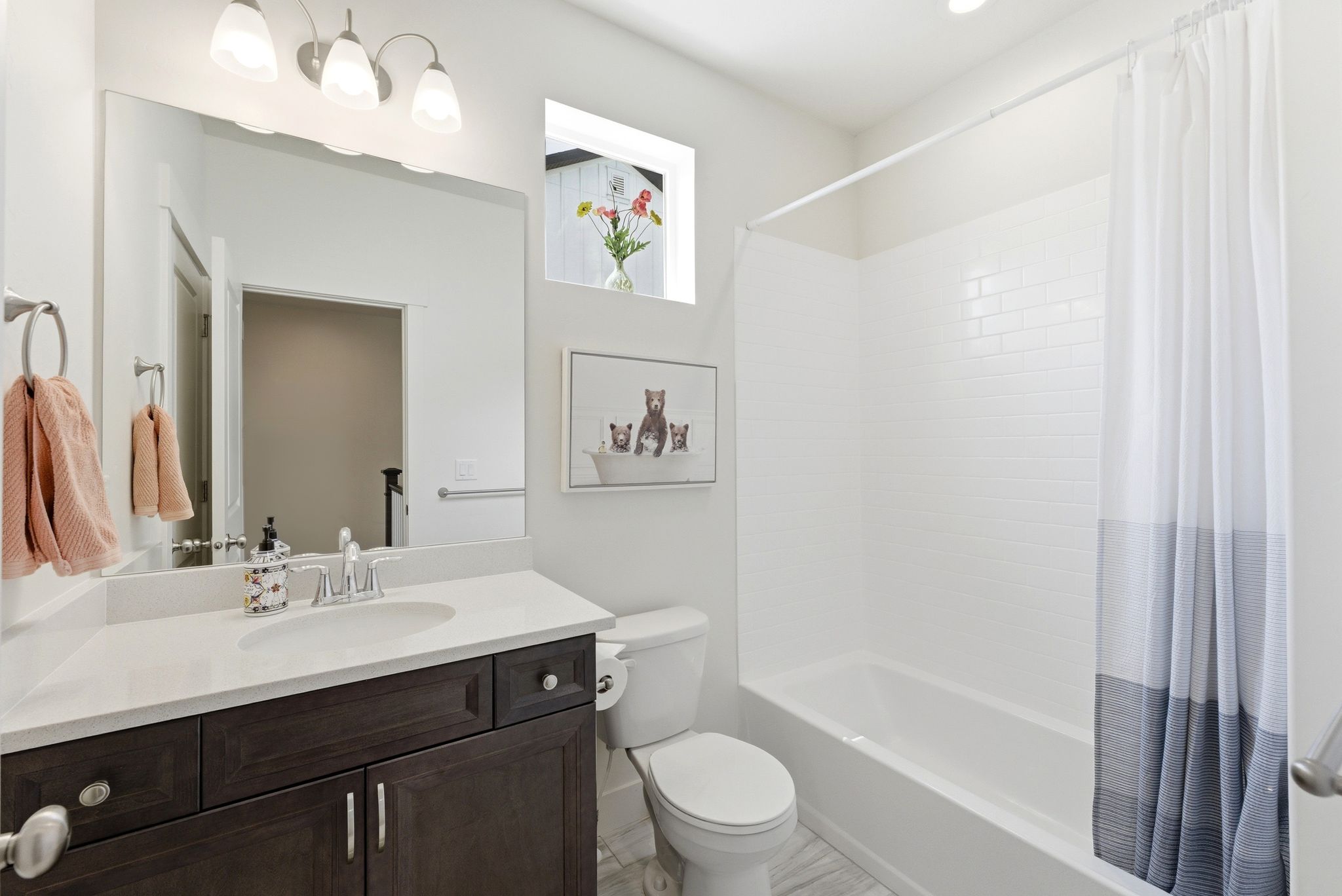 Bathroom featuring a dark wood-finish vanity with a light countertop, an integrated sink, and a chrome faucet