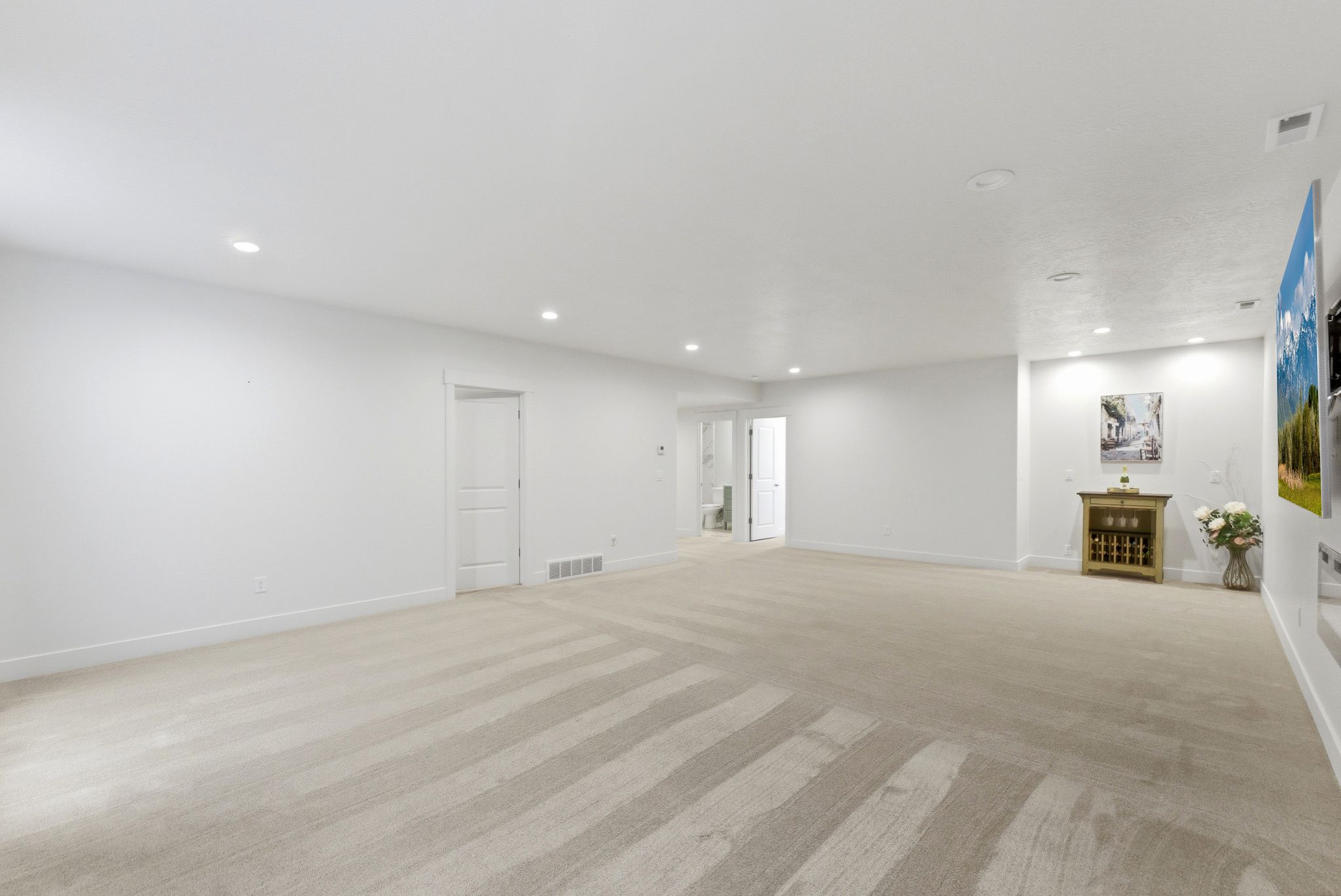 Spacious room featuring light-toned carpeting, recessed ceiling lighting, and white walls