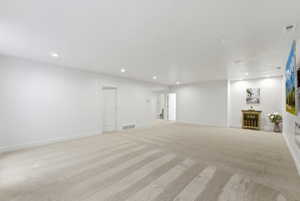 Spacious room featuring light-toned carpeting, recessed ceiling lighting, and white walls