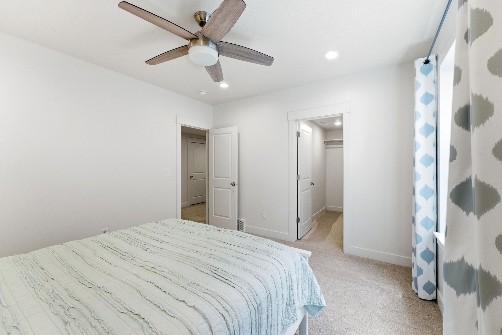 Carpeted room with a ceiling fan featuring wood-finish blades and a central light fixture