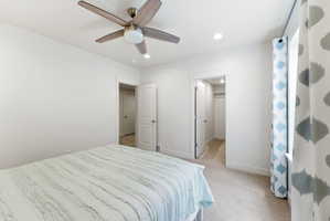 Carpeted room with a ceiling fan featuring wood-finish blades and a central light fixture