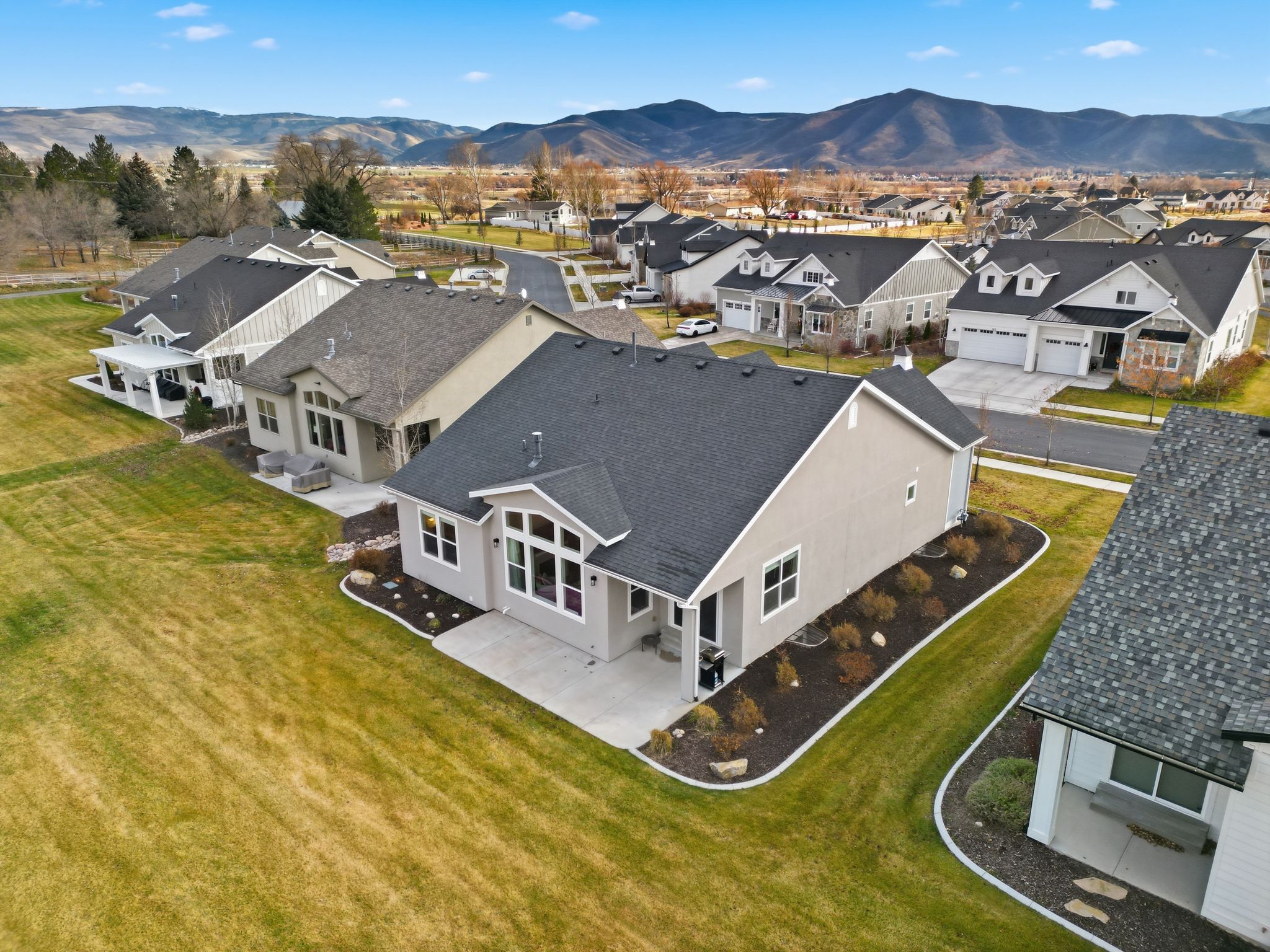 Aerial perspective showcasing a modern residence with a dark shingle roof and light-colored siding