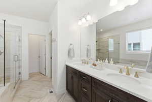 Double vanity with dark wood-finish cabinetry, white countertops, and gold-toned fixtures