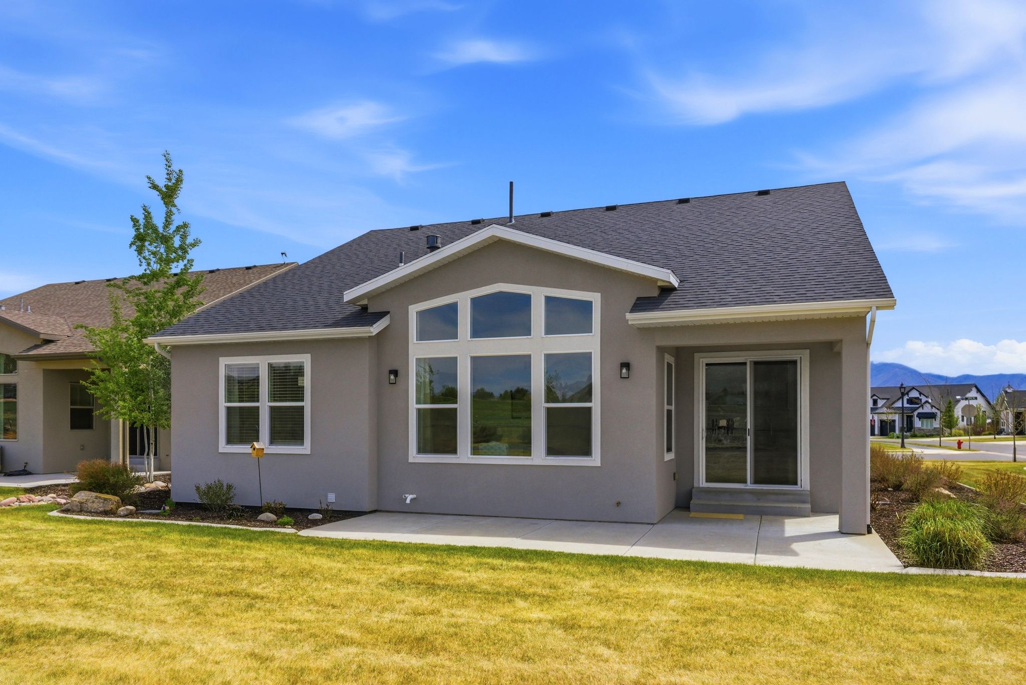 Rear exterior featuring a large patio, stucco siding, and a dark shingle roof