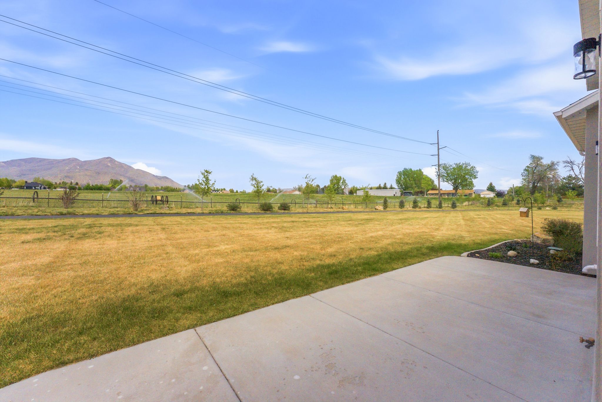 Expansive grassy yard with mountain backdrop and sprinkler system