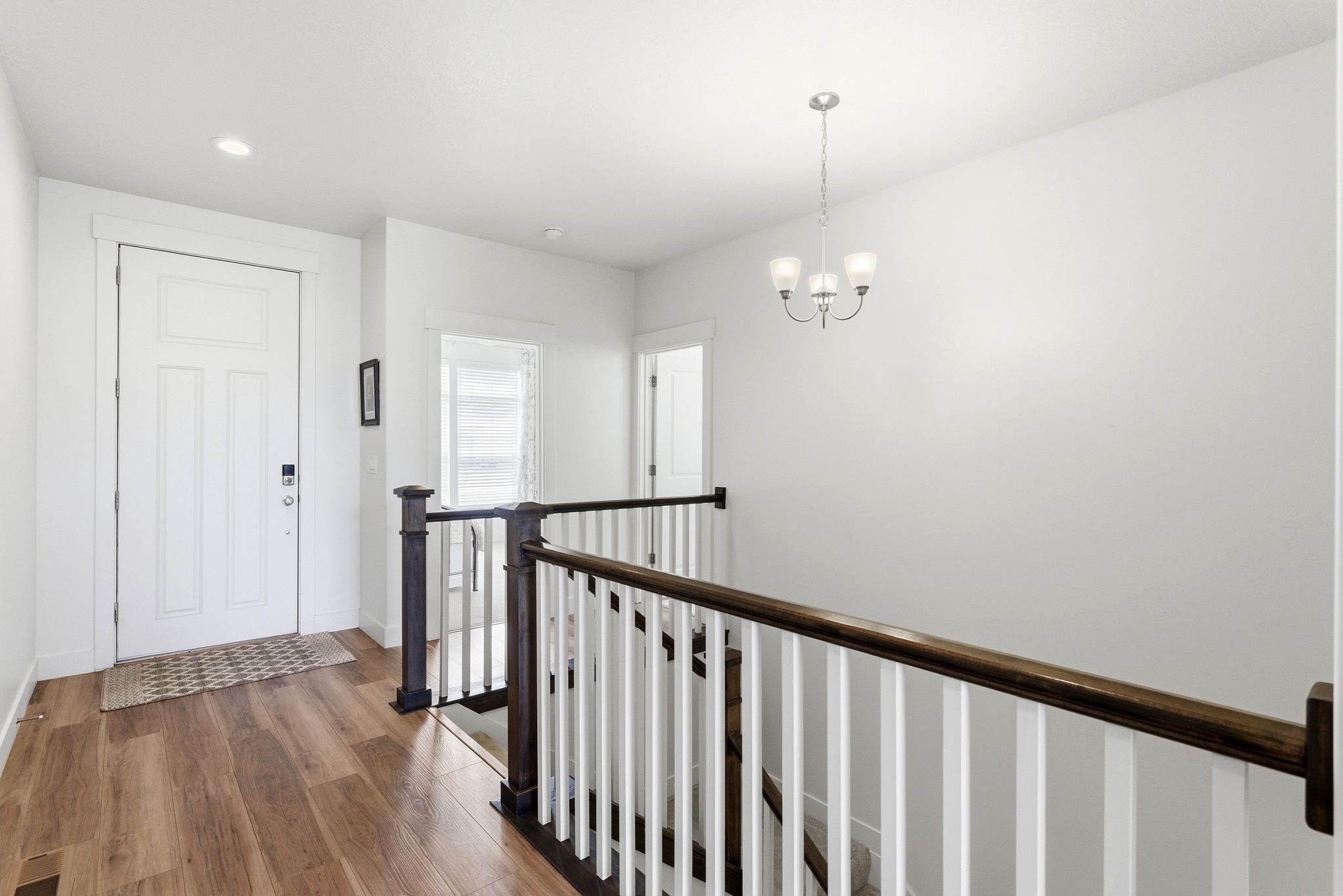 Entryway featuring wood-finish flooring, white paneled door, and recessed lighting