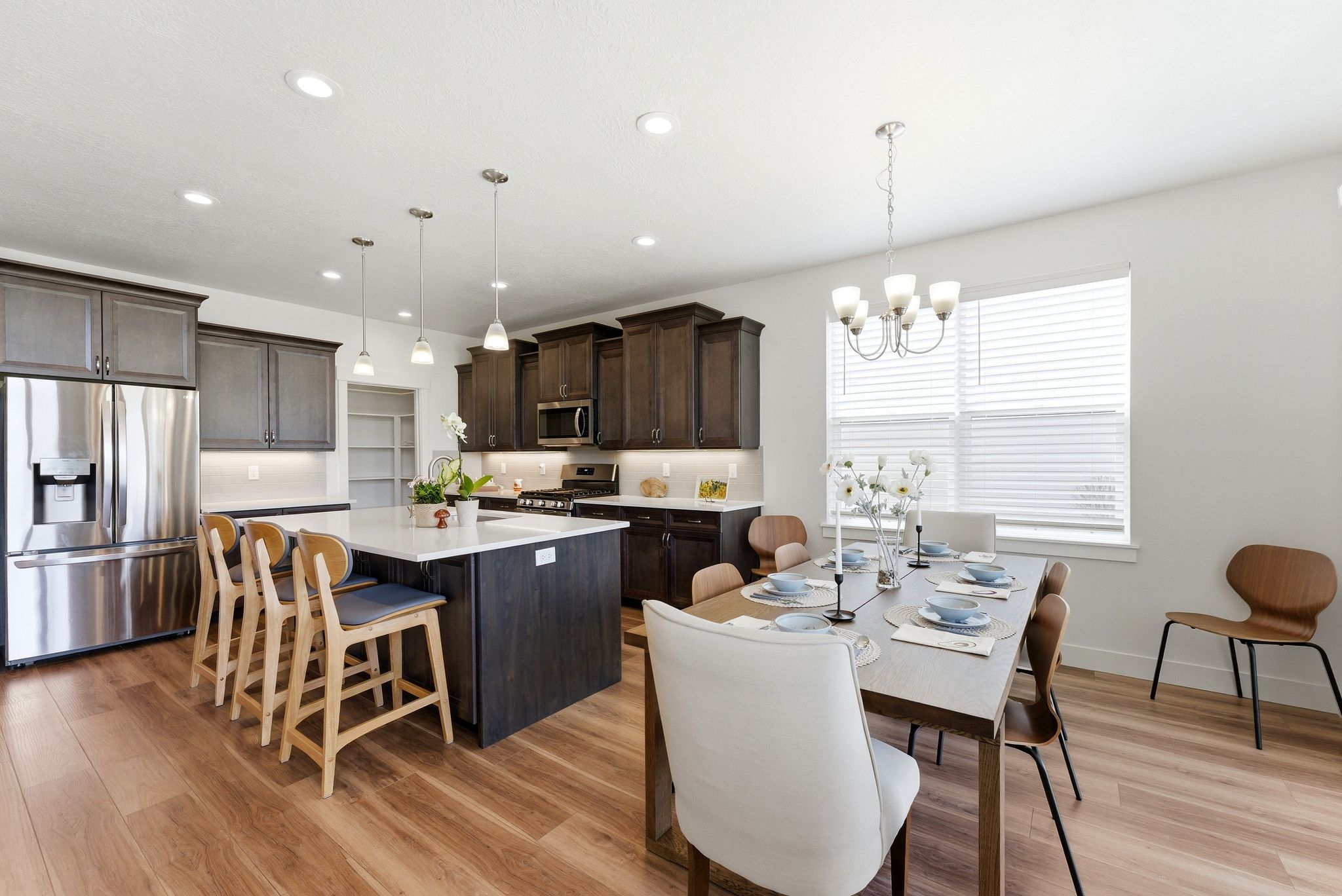 Open-concept kitchen and dining area featuring wood-finish flooring, recessed lighting, and a kitchen island with seating