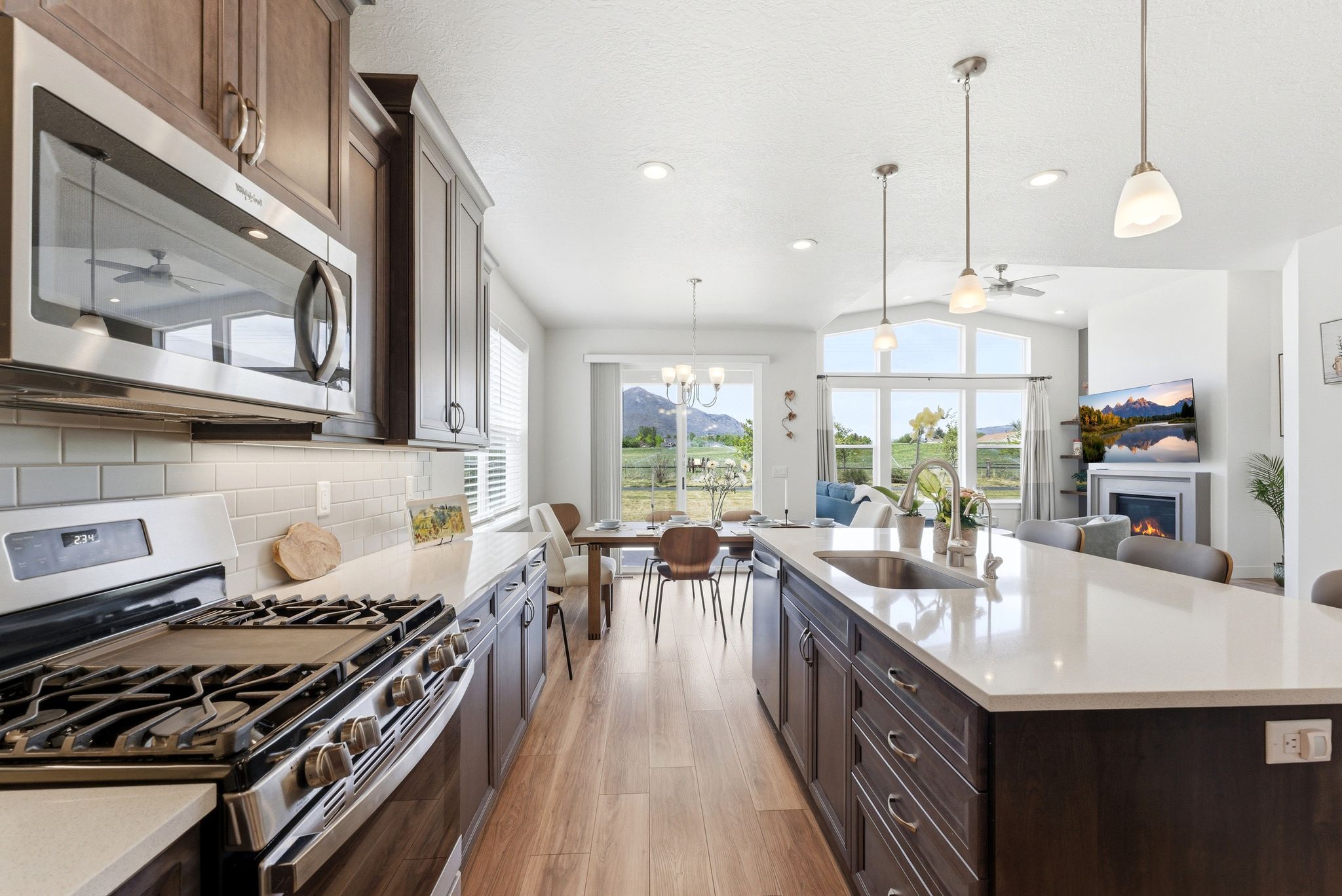 Gourmet kitchen with stainless steel appliances, white subway tile backsplash, light wood-finish flooring, and a spacious island featuring an undermount sink